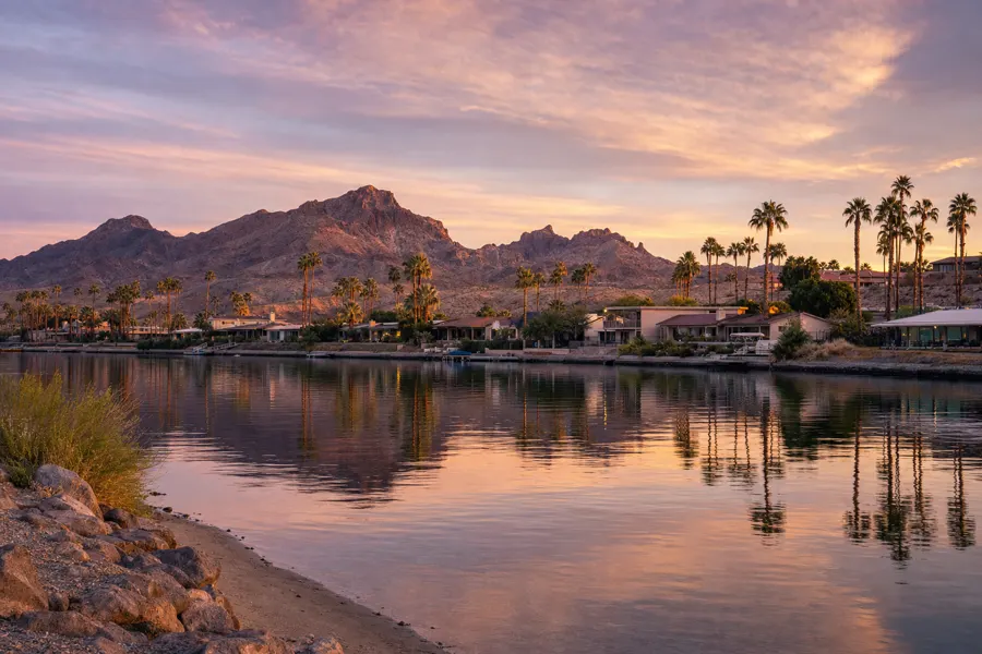 Bullhead City, Arizona riverfront homes with palm trees and desert mountains at dusk