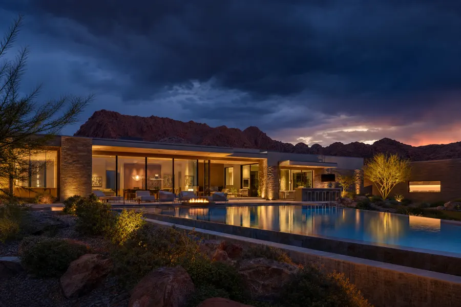 Contemporary desert estate at twilight with infinity pool and red rock backdrop