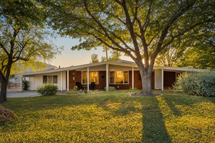 Mid-century brick ranch home shaded by mature trees at golden hour